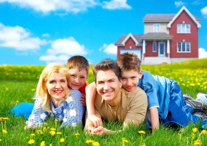 Family lying down in a field with a red house in the background